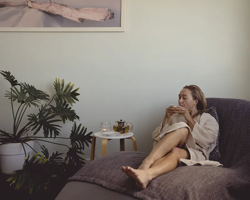Woman laying on chaise drinking a cup of tea